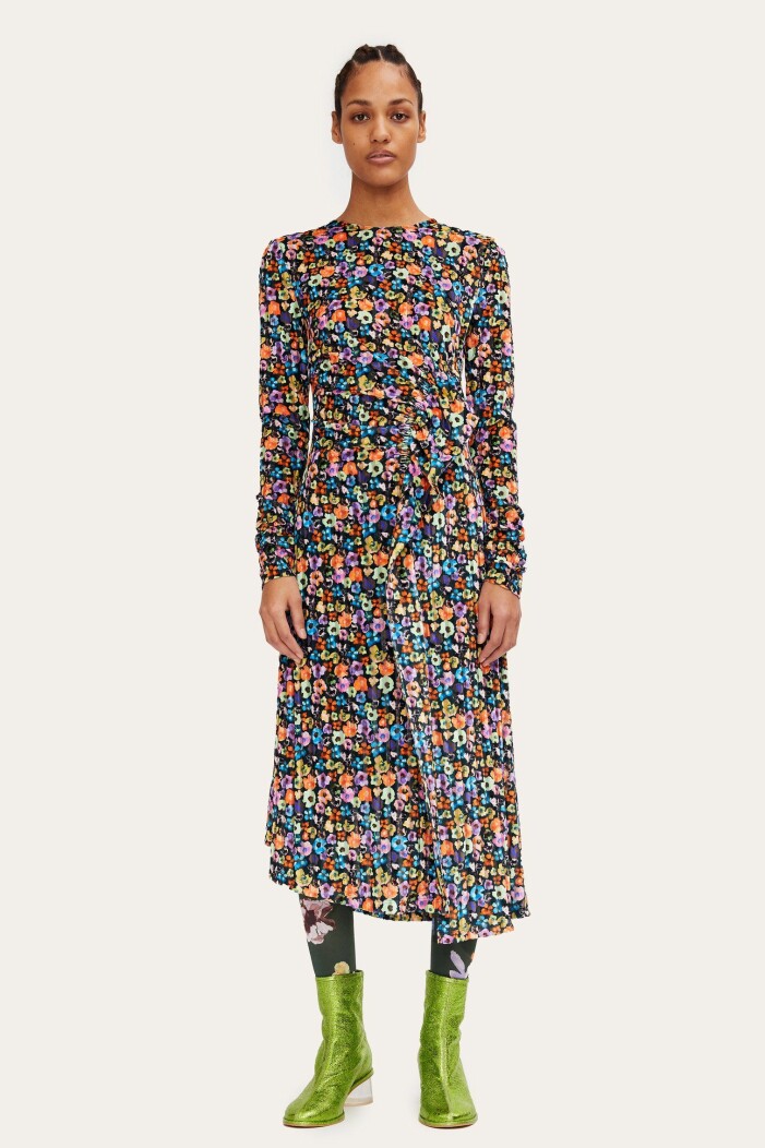 Klänning, Stine Goya. Modell med klänning med färgglatt blommönster. Klänningen har långa ärmar och slutar på vaden. På modellen är klänningen stylad med metallicgröna ankelboots. Outfit från Stine Goya.