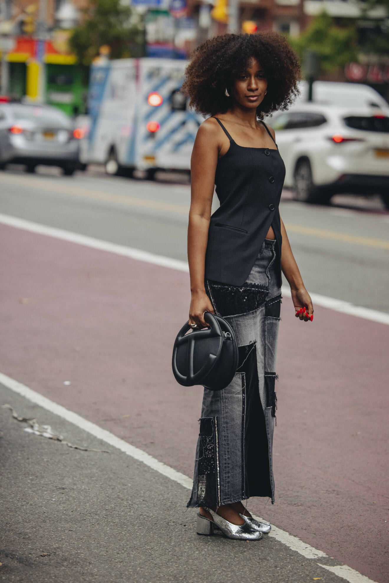 Streetstyle-outfit med en lång lappad jeanskjol, svart kostymväst och silverskor.