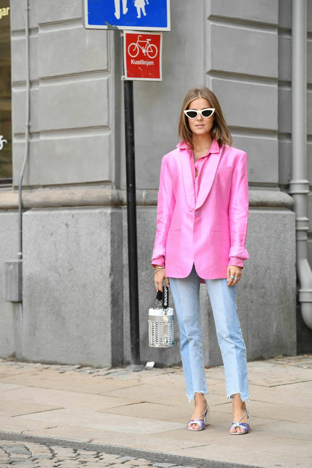 streetstyleoutfit med ljusa jeans, rosa kavaj, rosa skjorta, klackar och metallicväska
