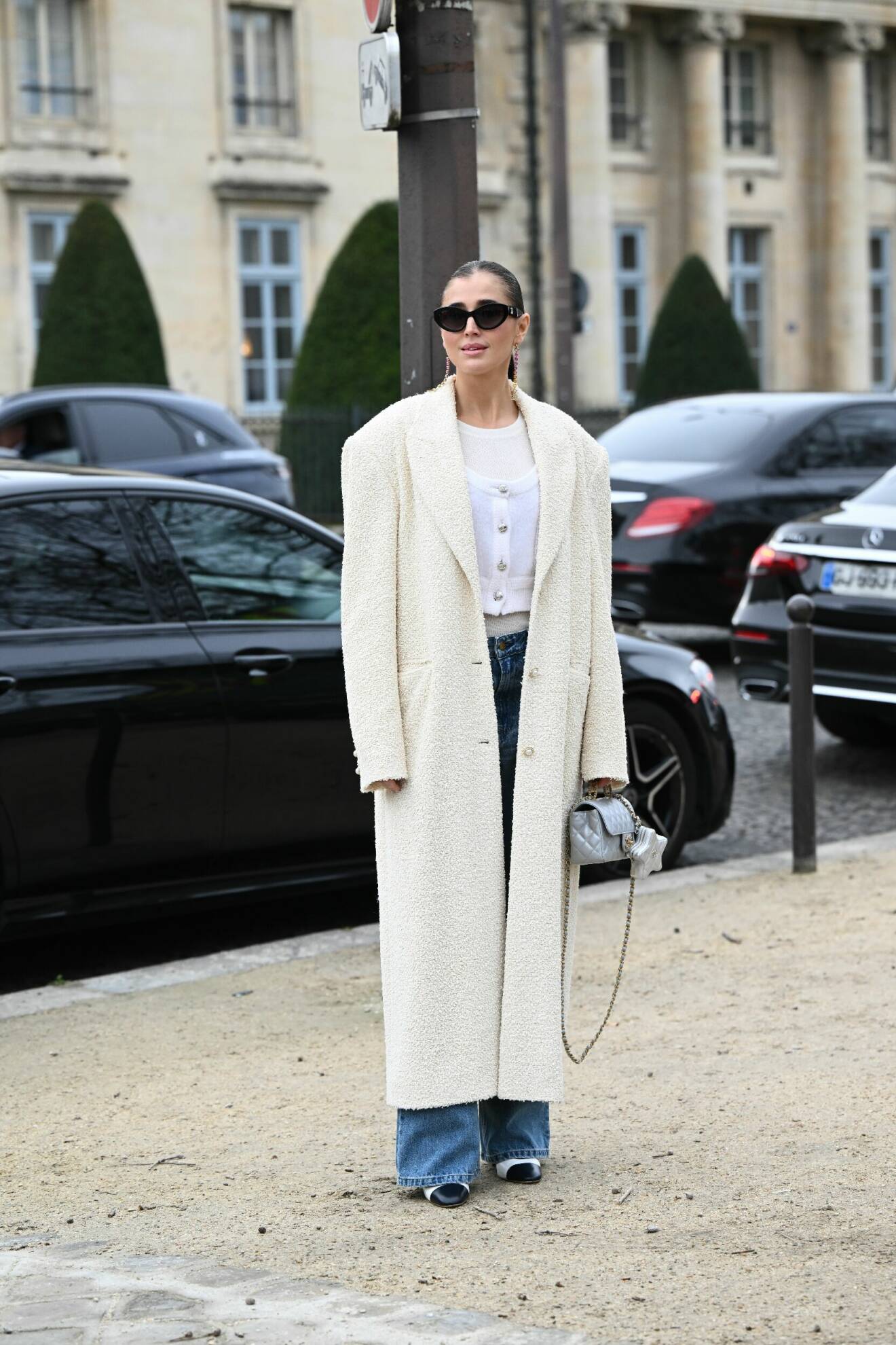 Streetstyle-outfit med vit kapp, jeans, vit topp och svarta solglasögon