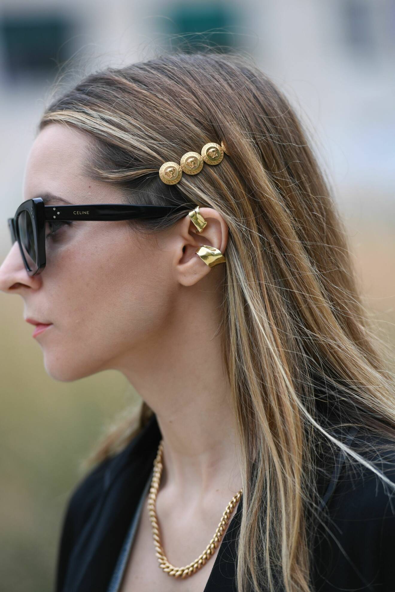 En gäst vid modeveckan i Milano bär flera olika guldsmycken tillsammans.
