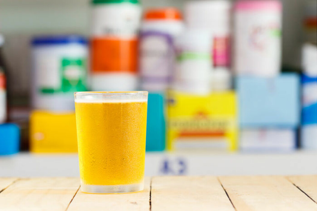 Du kan köpa vätskeersättning både med och utan smak. Bild: Shutterstock/IBL Glas med gul vätska i form av vätskeersättning.