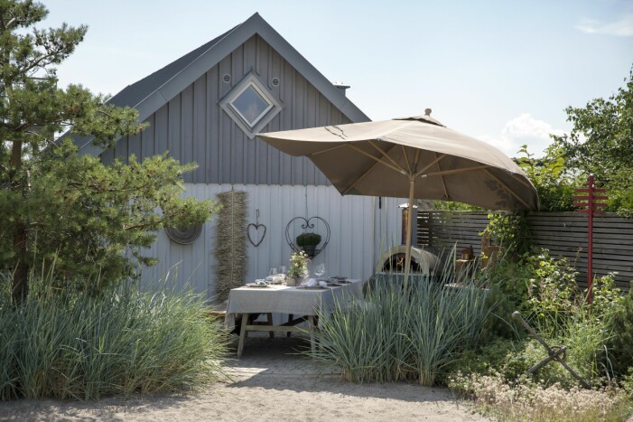 Trädgårdens middags- och pizzaugnshörna, med markrundel av gatsten, skapades sommaren 2019 efter att Maria funderat igenom vad hon ville göra av den platsen – innan dess fanns bara sand där. Villa vid stranden i skåne.
