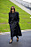 kvinna iklädd lång svart kappa och svart skjorta.