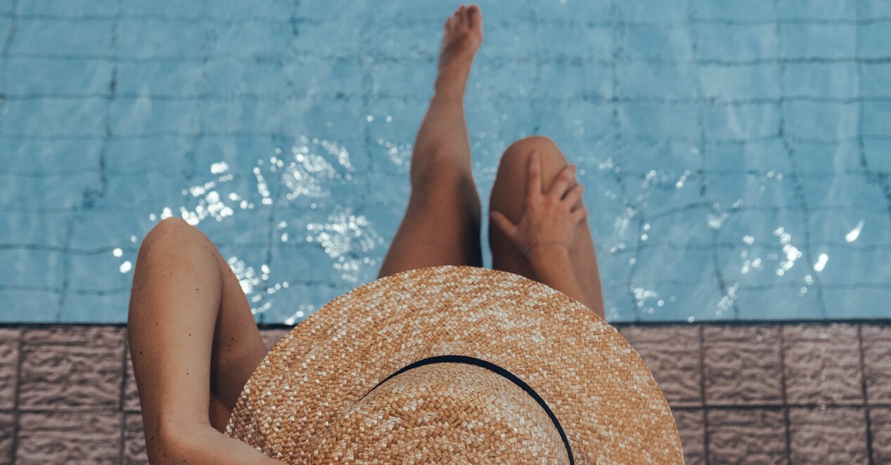 kvinna med bruna ben som sitter vid poolkanten