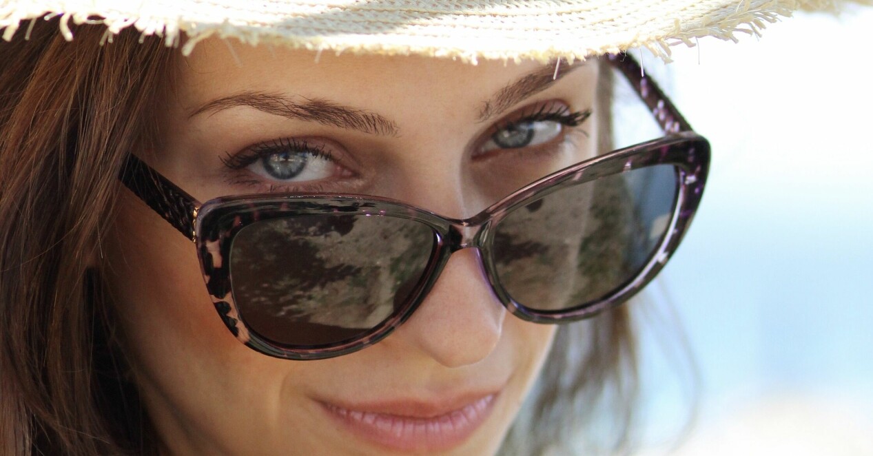 kvinna med solhatt och solglasögon